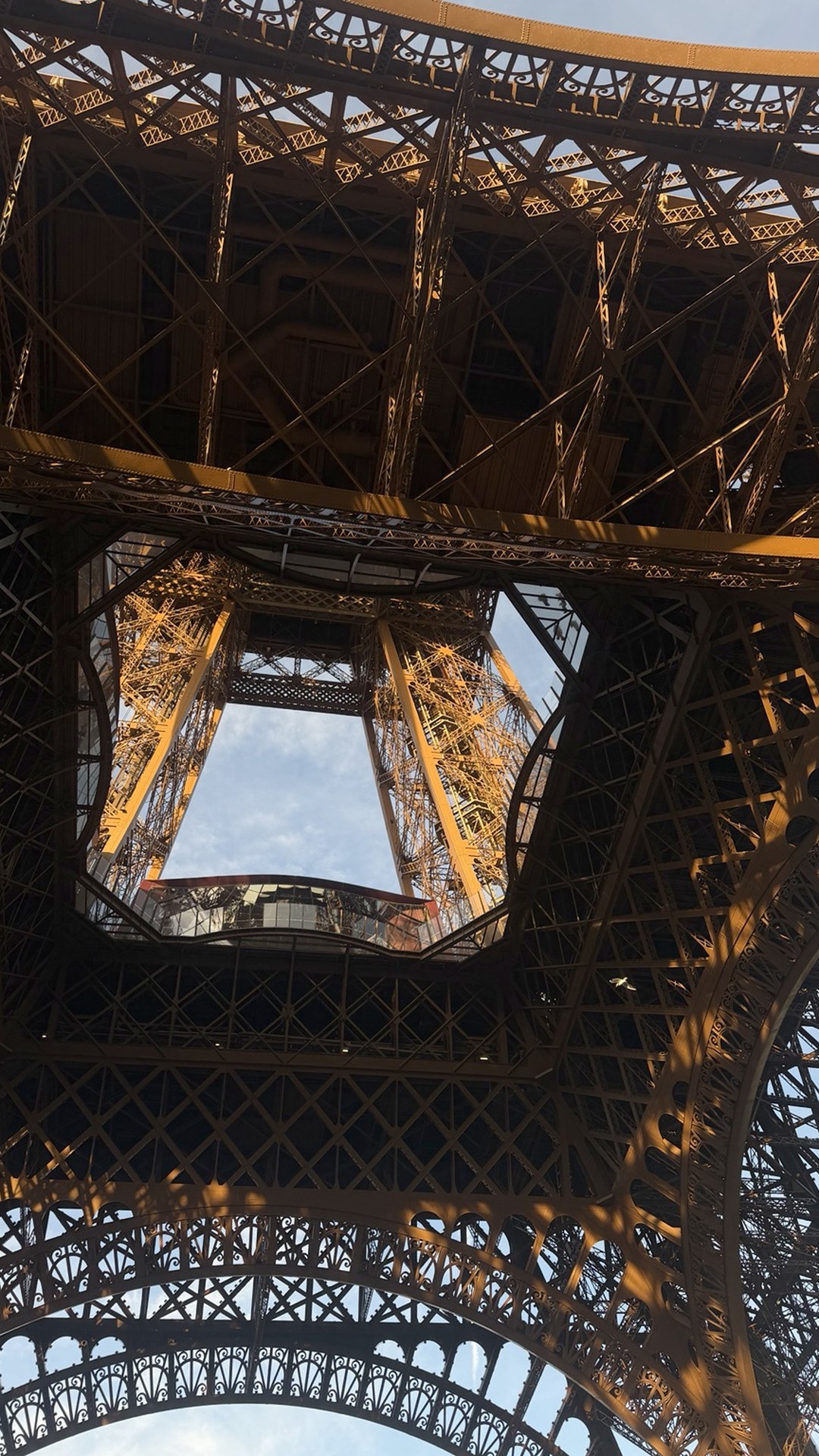 Looking upward through the Eiffel Tower arches and layered iron framework