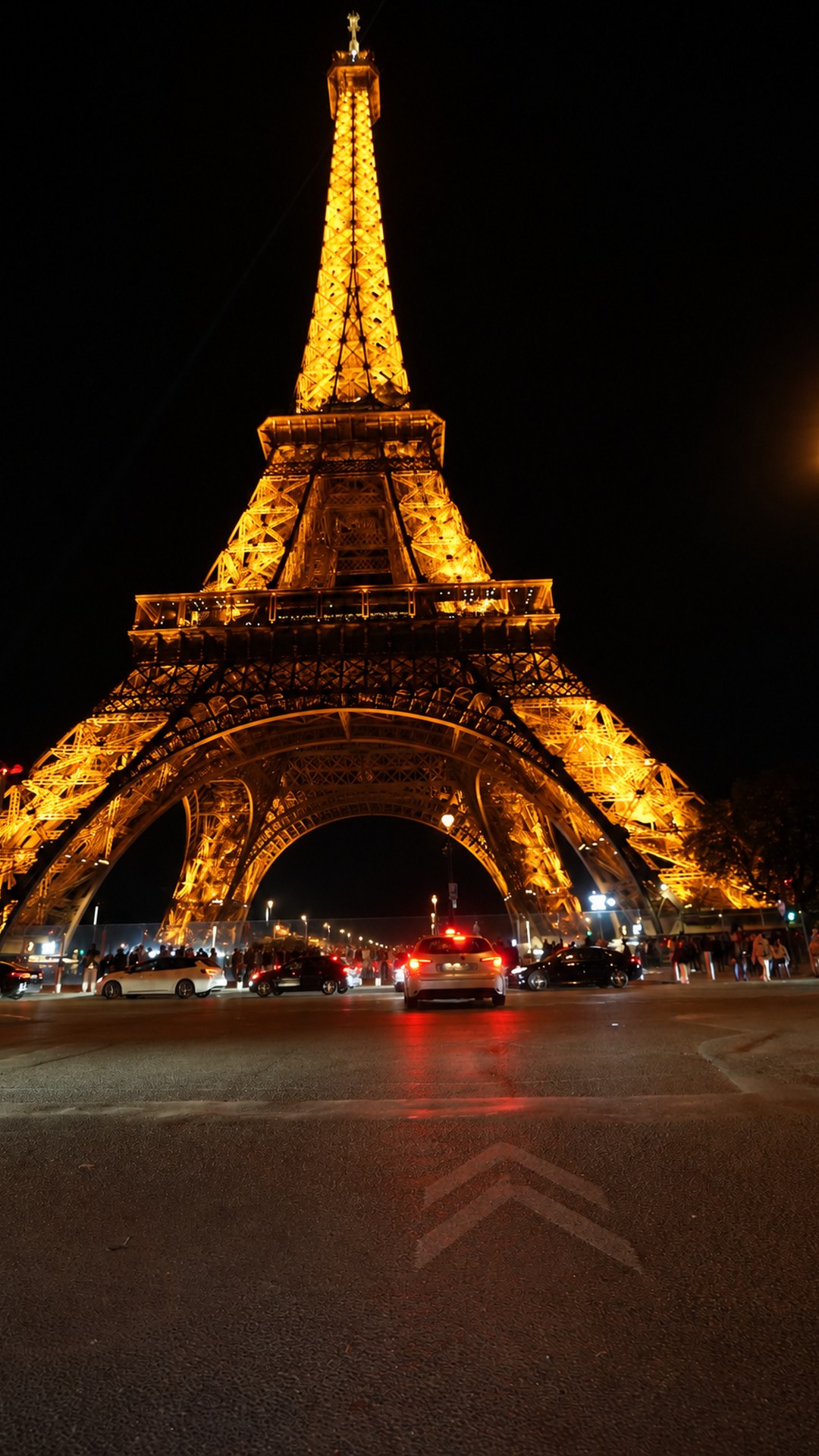 The illuminated Eiffel Tower rising above the street at night