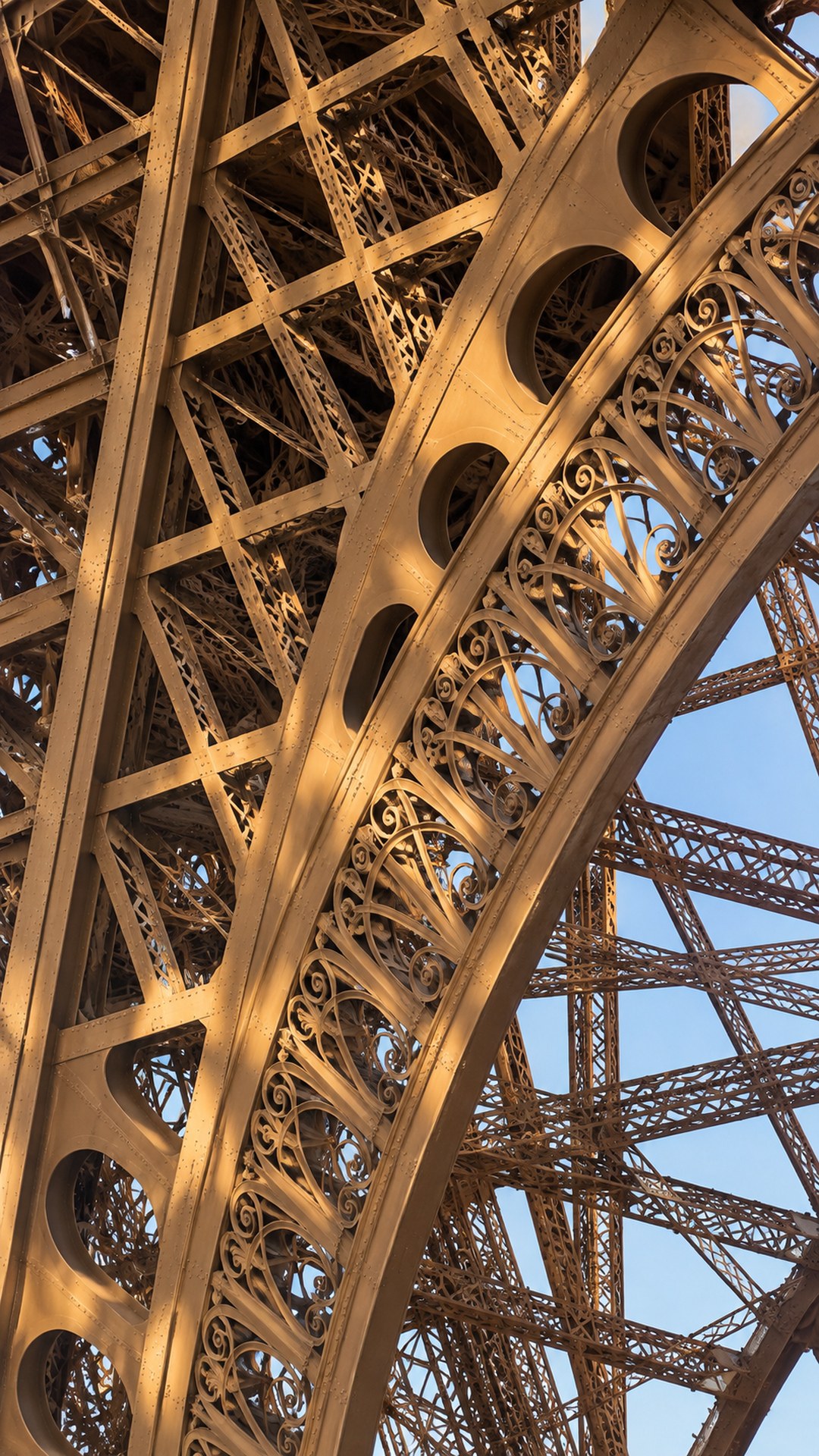 A close view of curved ironwork, decorative scrolls and riveted beams