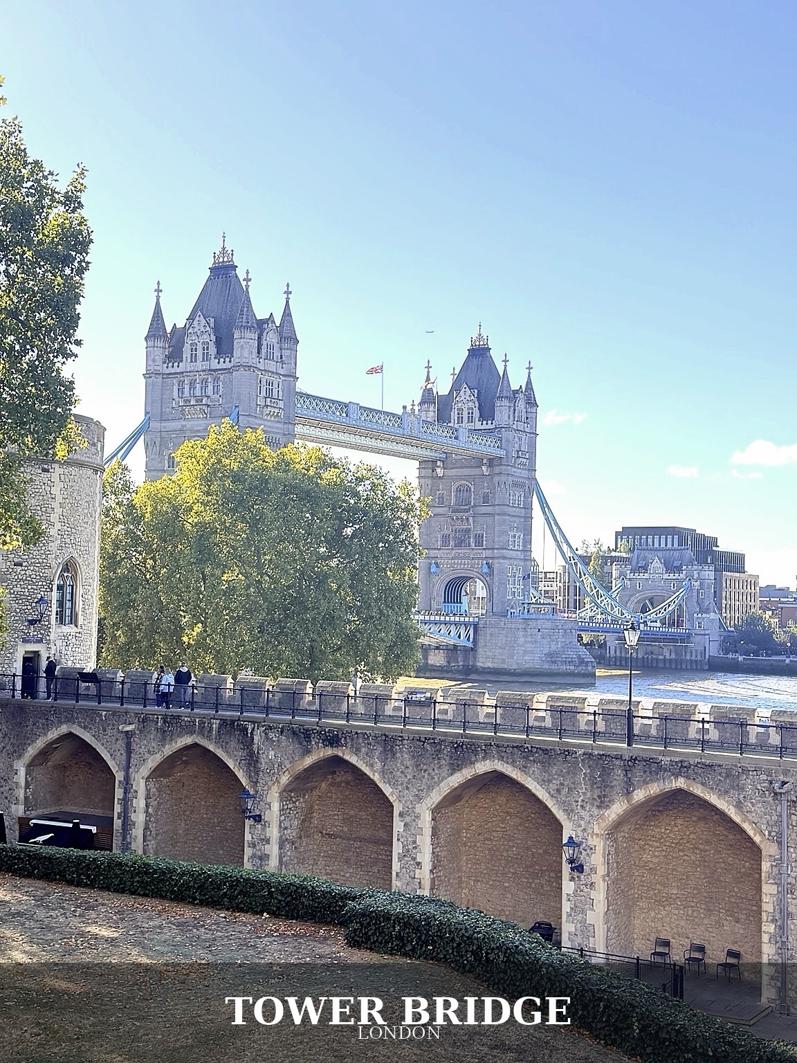 Tower Bridge framed by the grounds of the Tower of London, with the original Tower Bridge caption