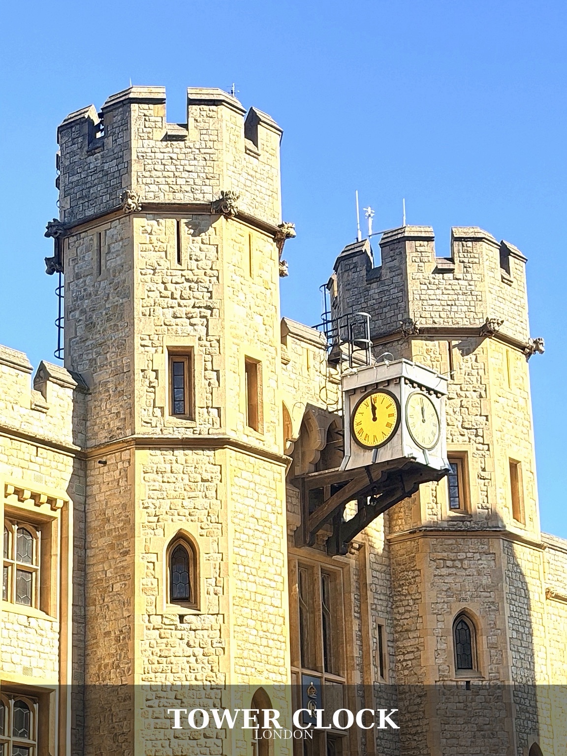 A yellow clock between stone towers, with the original Tower Clock caption
