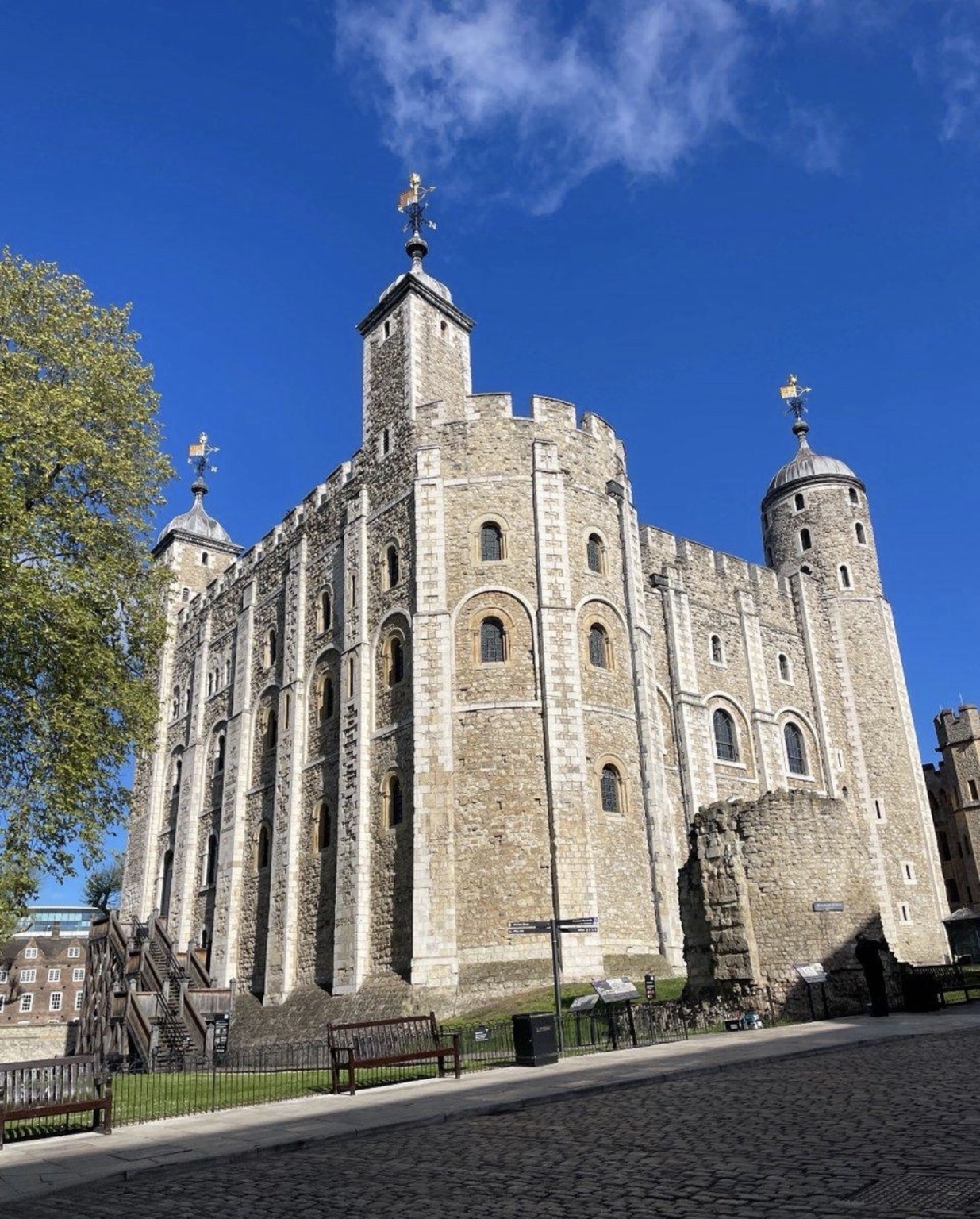 The stone towers of the Tower of London beneath a blue sky
